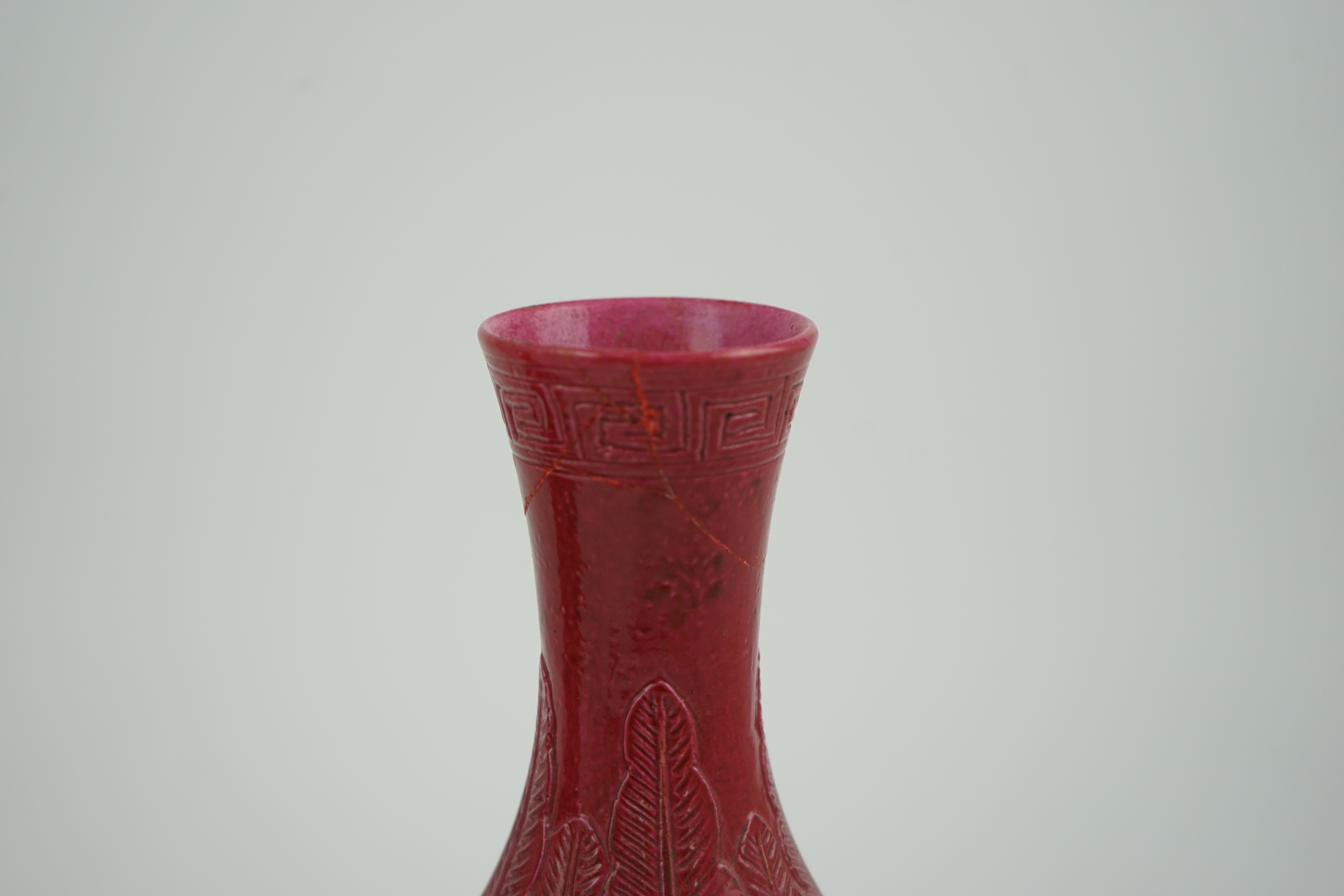 A pair of Chinese ruby ground ‘lotus’ bottle vases, late 19th century, each carved in relief with lotus flowers, scrolling tendrils and leaves, both with carved stands, 24cm high. Condition - one vase the neck broken bot